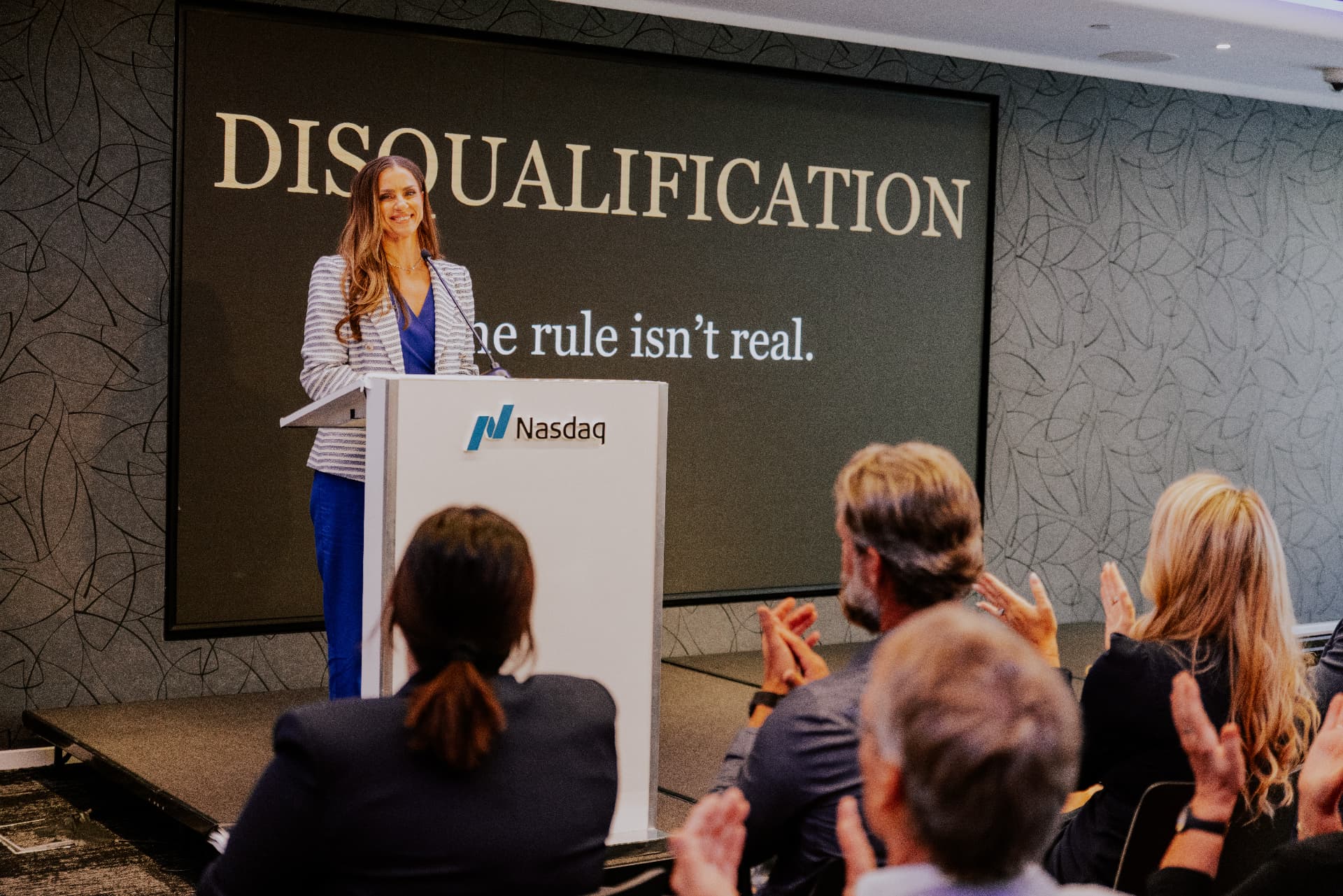 MaryAnne Karstadt delivering a keynote at a Nasdaq podium in front of a live audience